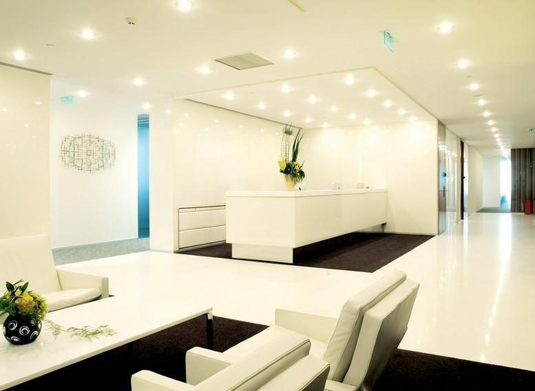 Bright white reception area with a minimalist front desk and recessed lighting.