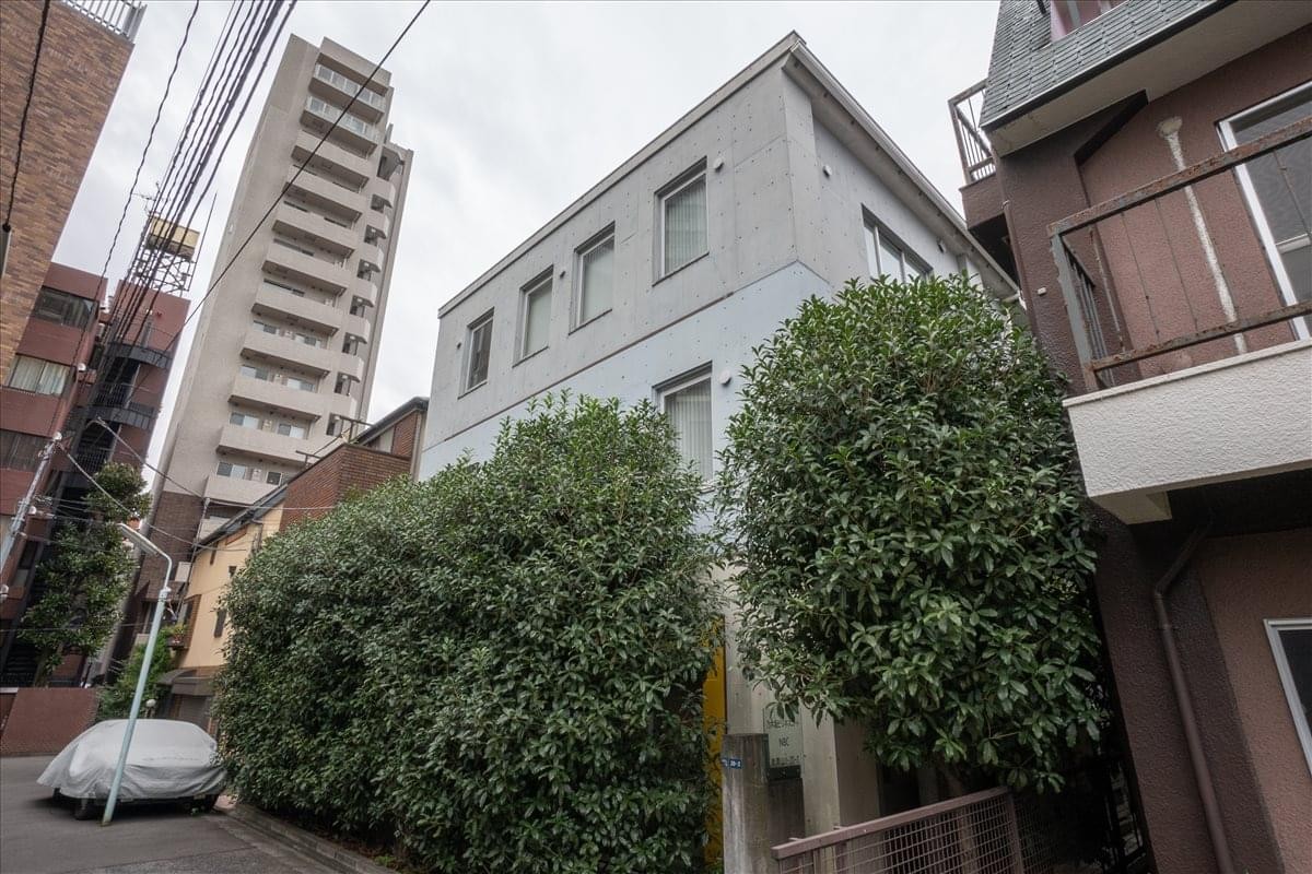Exterior of Nogizaka Business Court, Minami Aoyama, Minato-ku, Tokyo featuring light grey masonry and green hedges.