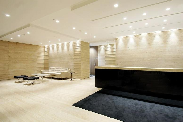 Minimalist reception area with a sleek black desk and soft recessed lighting.