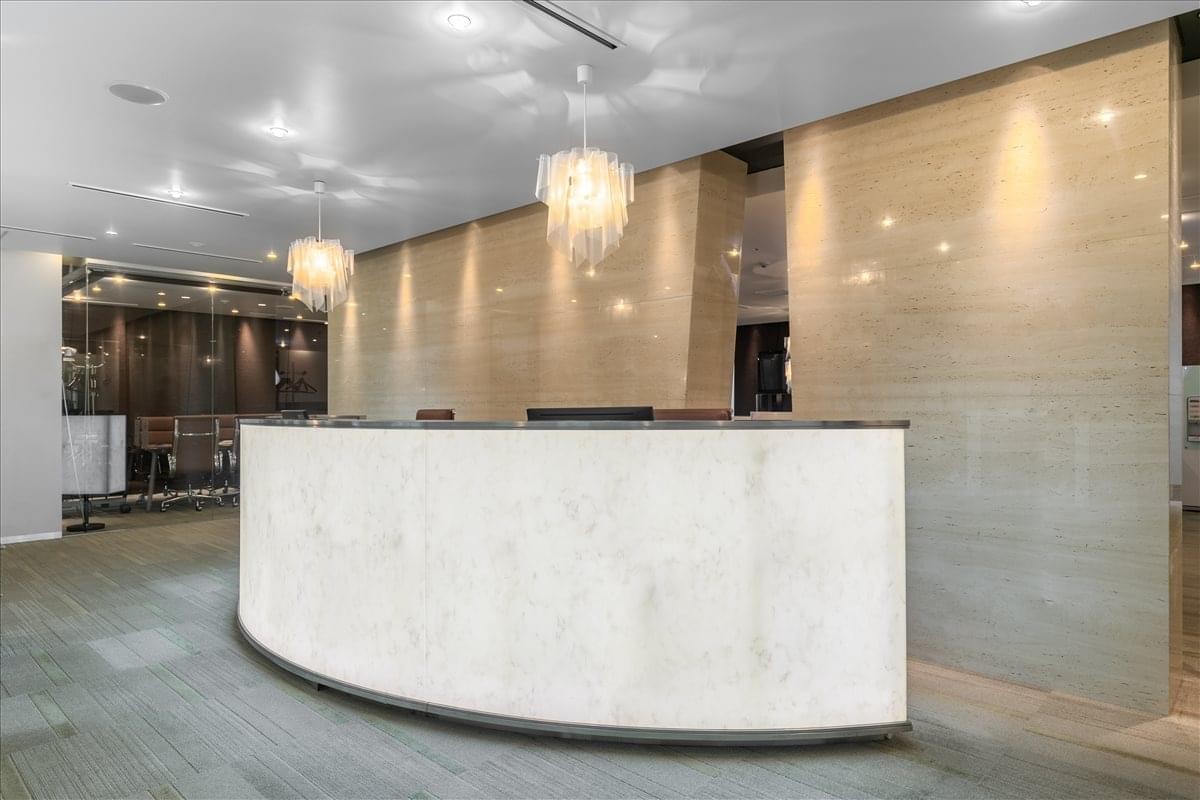 Sleek curved marble reception desk with elegant crystal chandeliers.