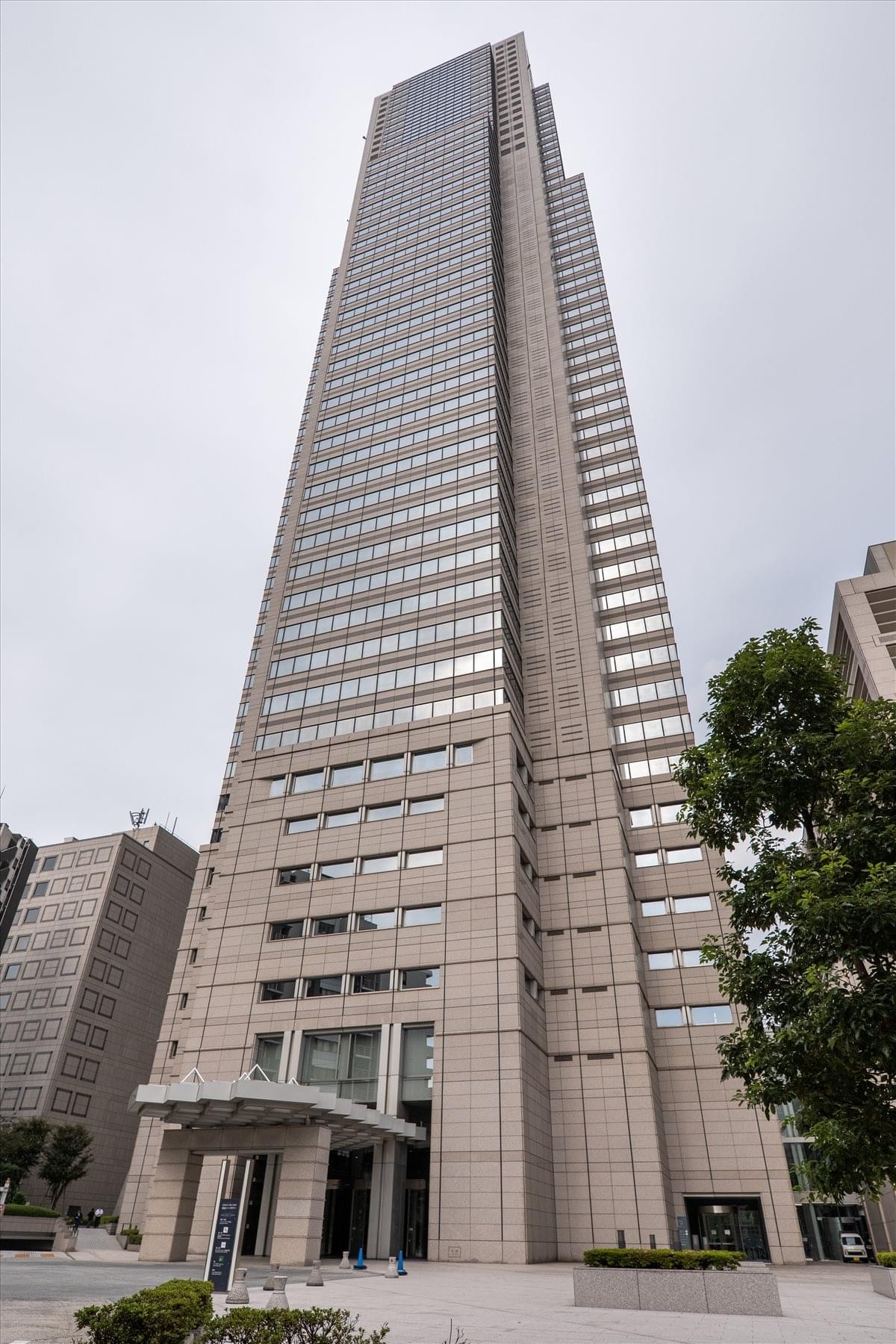 A low-angle exterior shot of the towering glass and stone Shinjuku Park Tower.