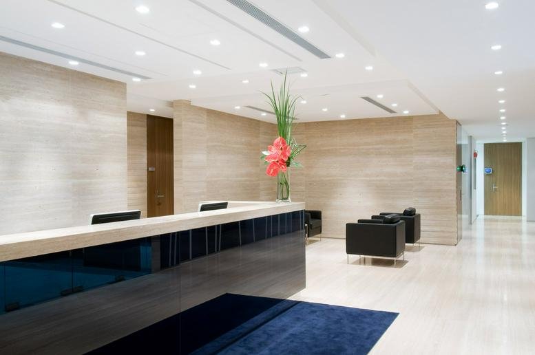 Bright reception area with a dark wood desk, stone walls, and a vibrant floral arrangement.