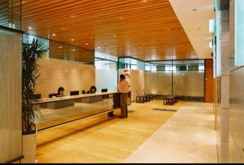 Spacious reception area with a wooden ceiling, stone flooring, and a glass-fronted desk.
