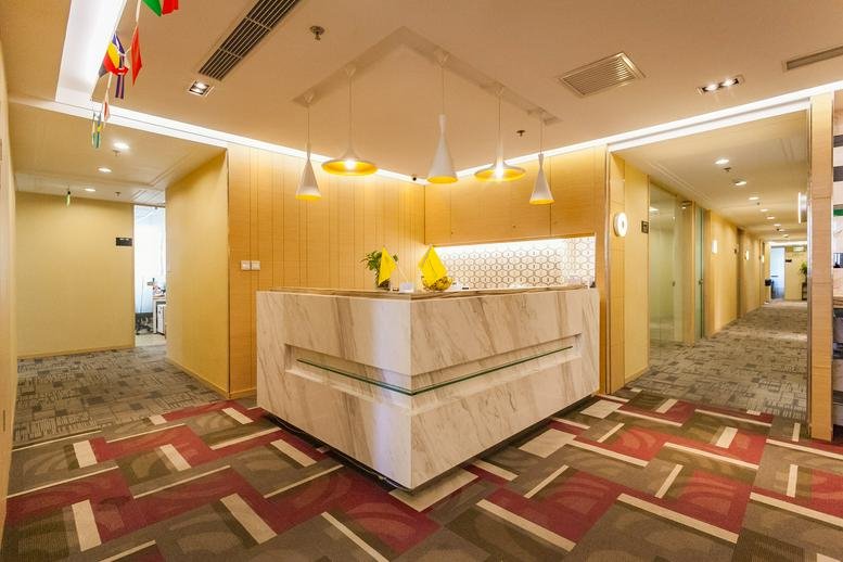 Bright reception area featuring a marble desk, pendant lighting, and patterned carpet.