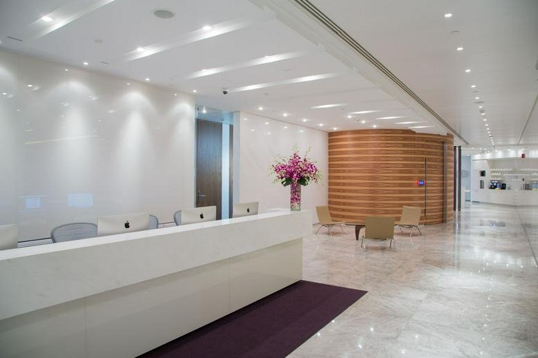Bright, white reception area with a marble floor and curved wooden feature wall.