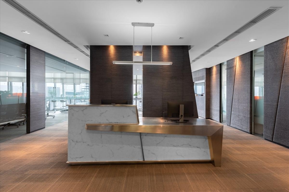 Sleek modern reception area with a stone and wood front desk and warm lighting.