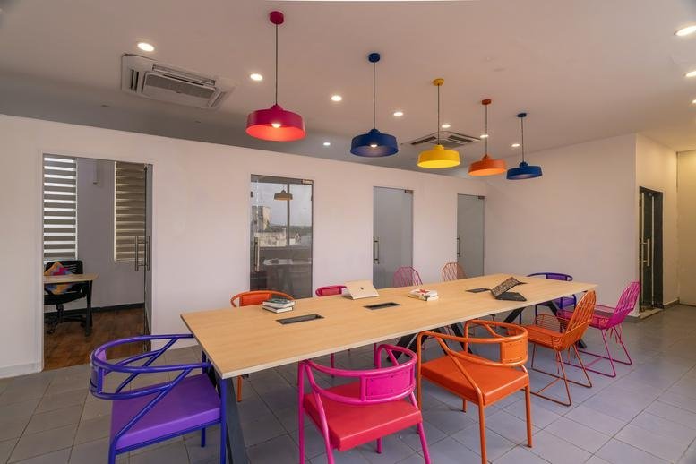 Spacious communal coworking area at Plot No, 72A, Suraj Nagar East with vibrant chairs and pendant lights.