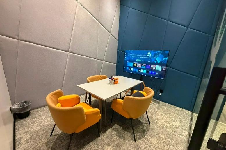 Private meeting room at Prince Sultan Road with yellow armchairs and a wall-mounted TV.