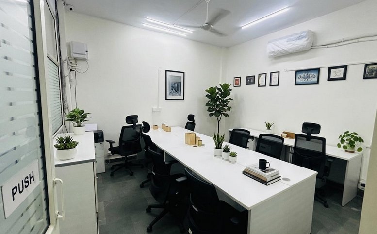 Spacious open-plan workspace at Rama Road featuring white desks, black chairs, and potted greenery.