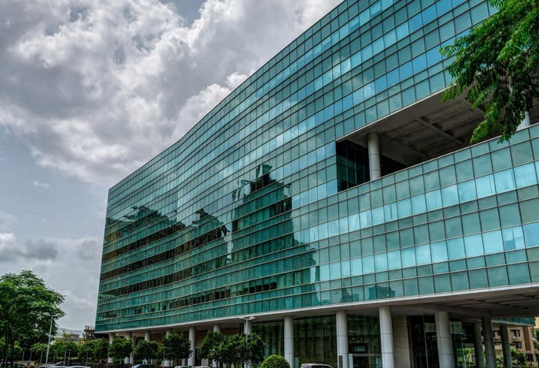 Exterior view of the glass-facade Redbrick Offices, Lodha Ithink building under a cloudy sky.