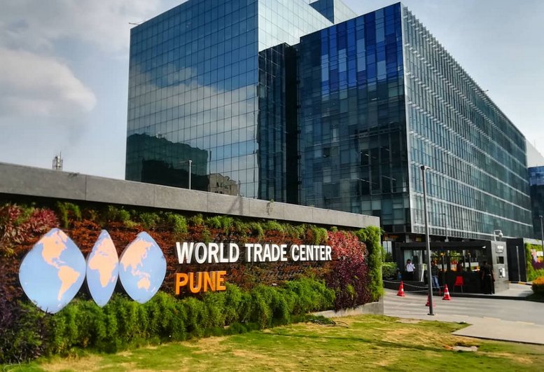 Exterior view of the Redbrick Offices, World Trade Centre, Kharadi with a green living wall and globe logo.