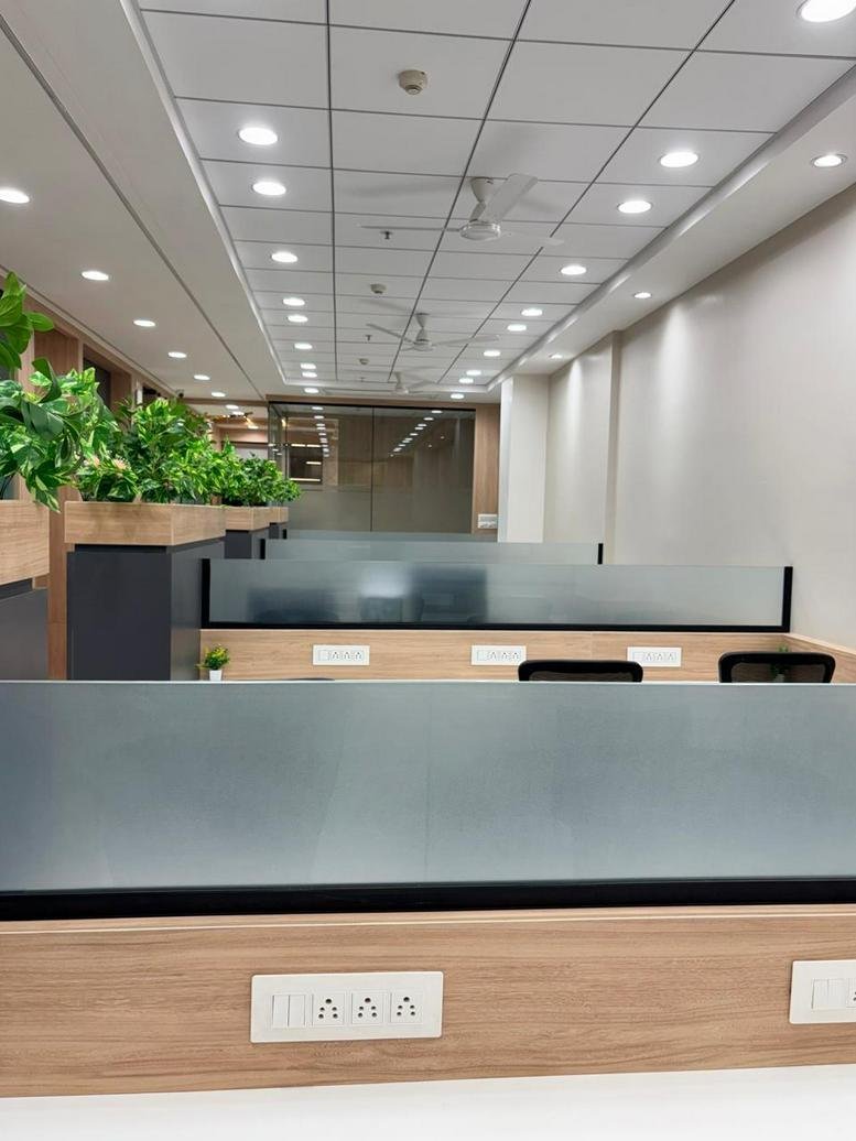 Spacious open-plan workspace at Destination Center 1 with greenery-topped partitions and bright ceiling lighting.