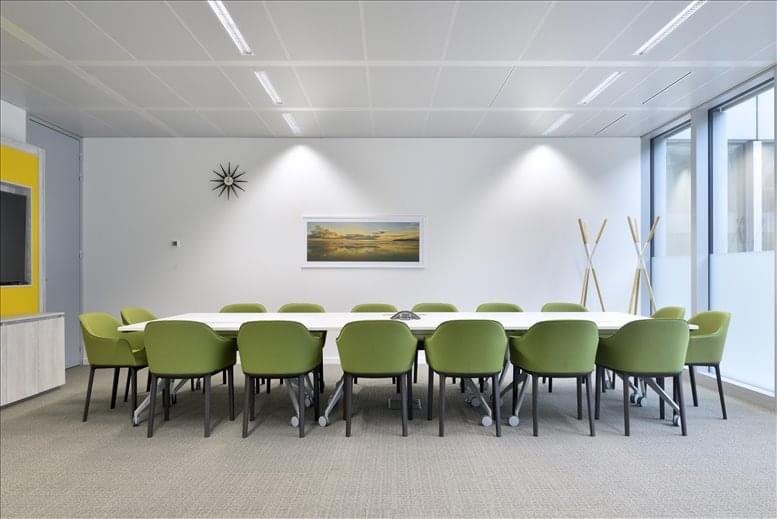 Conference room with long table and green chairs.