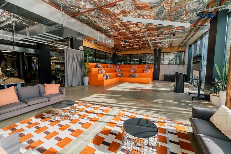 Creative breakout space with a stepped orange seating area and geometric patterned rug.