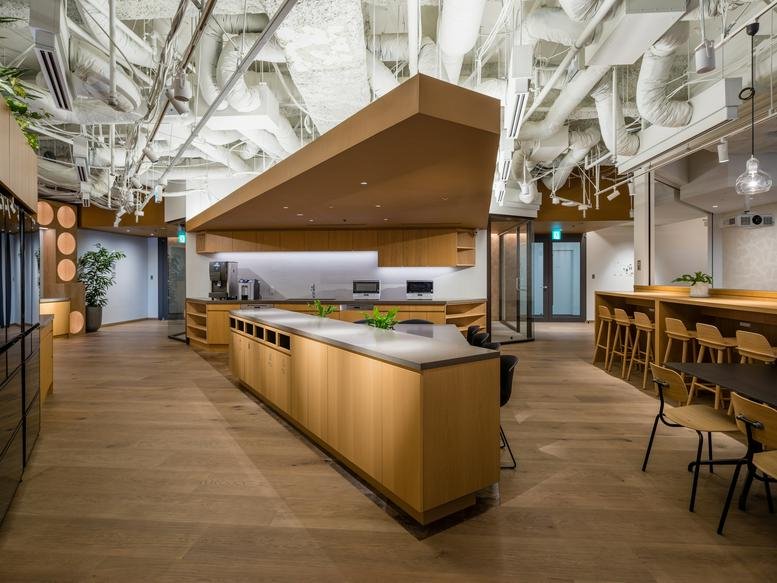 Toranomon Hills Business Tower office kitchen and breakout hub with exposed ceiling pipes.