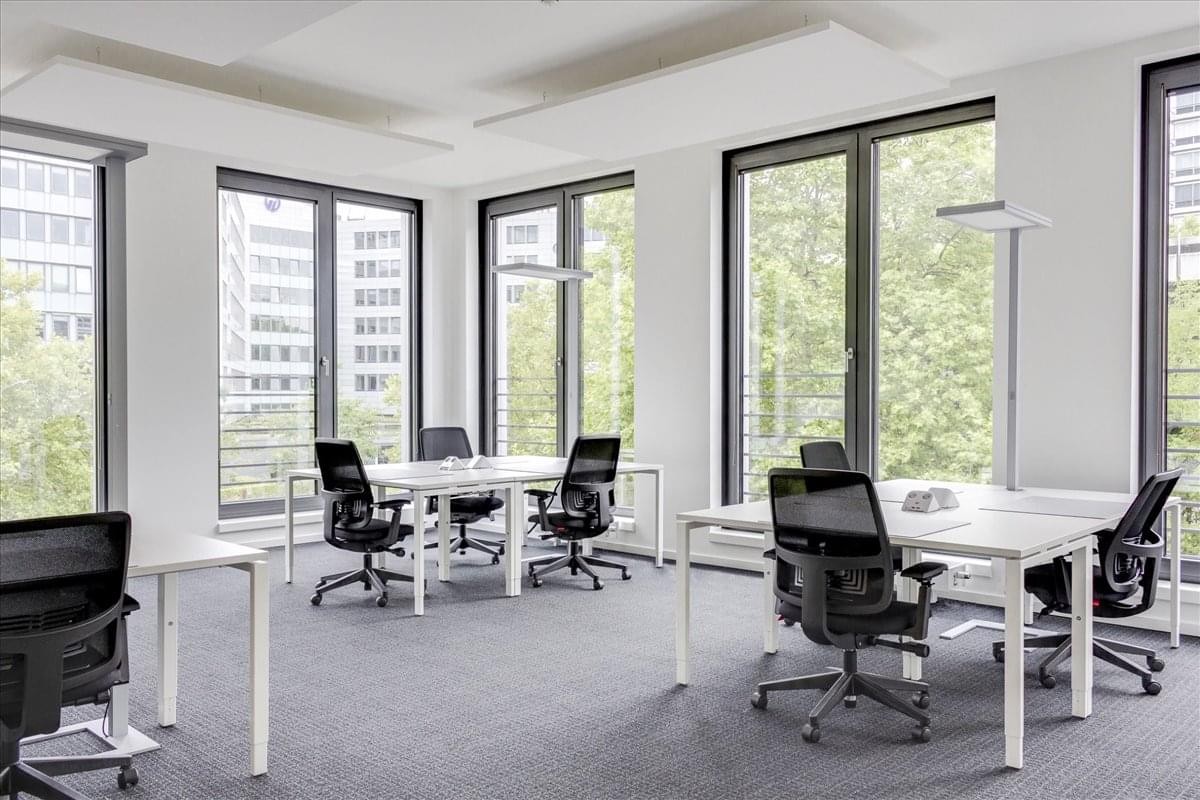 Spacious open-plan workspace at Elite 28 Building featuring white desks and large windows.