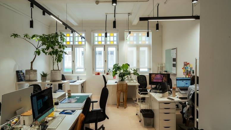 Bright open-plan office with multiple desks, lush indoor plants, and natural light at 1 Liang Seah Street.