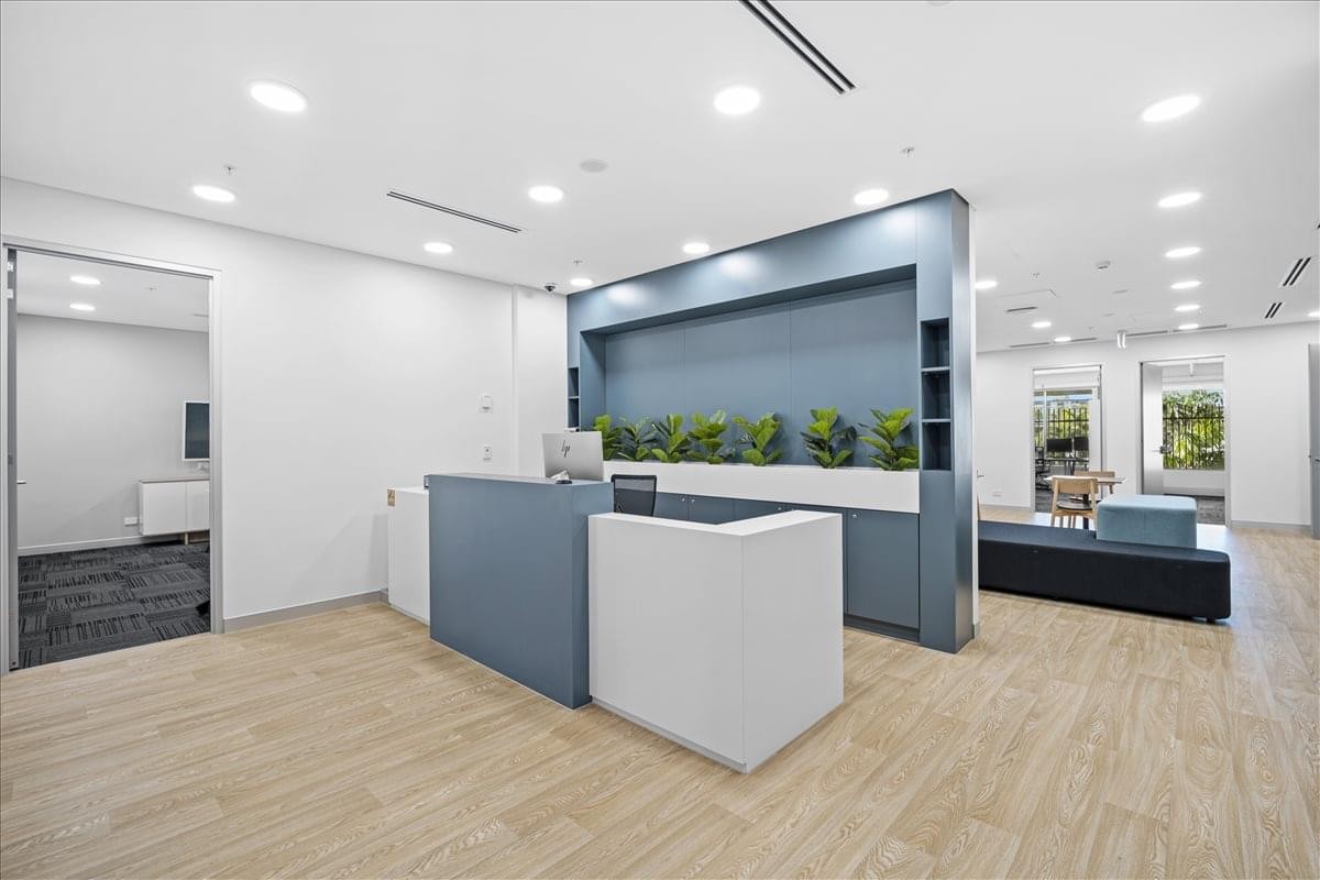 Sleek reception area at 1 Palmerston Circuit with a dual-tone desk and integrated greenery.