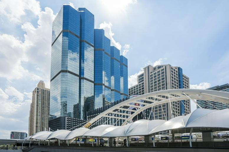 Exterior view of the glass-facade Empire Tower under a bright, cloud-flecked sky.