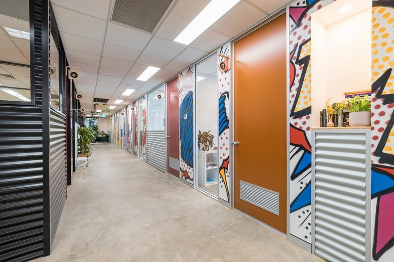A long hallway at 10-14 Wormald Street, Symonston ACT featuring vibrant pop-art wall murals and private office doors.