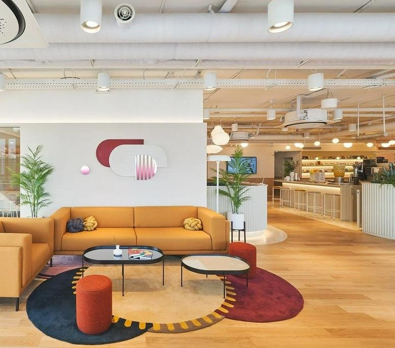 Spacious communal lounge at K-Square, 10 Gangnamdae-ro 94-gil, featuring a mustard sofa and colorful circular rugs.