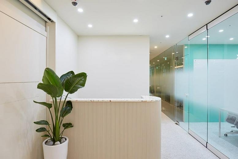 Bright reception area with a potted plant and modern wood-paneled desk at Hanil Novelia.