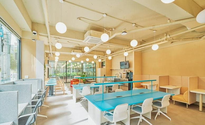 Spacious communal lounge at 10 Nambusunhwan-ro 333-gil with blue tables, white chairs, and globe pendant lights.