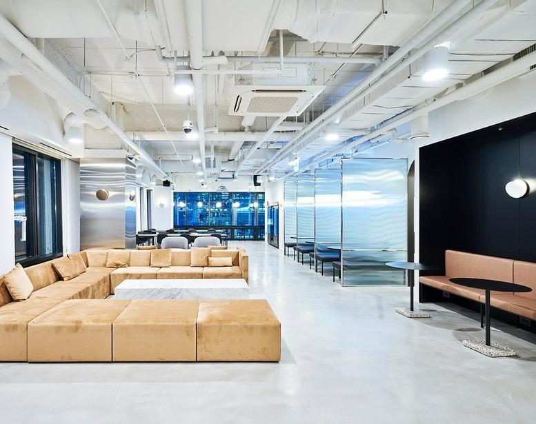Spacious lounge at 100, Cheonggyecheon-ro, Euljiro with tan modular seating and industrial ceilings.