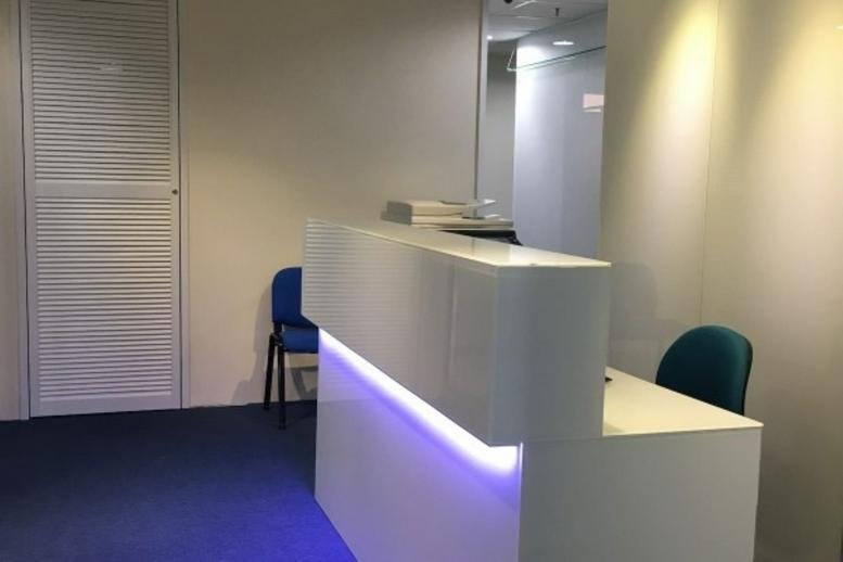 Minimalist white reception desk with blue accent lighting and seating at China United Plaza.