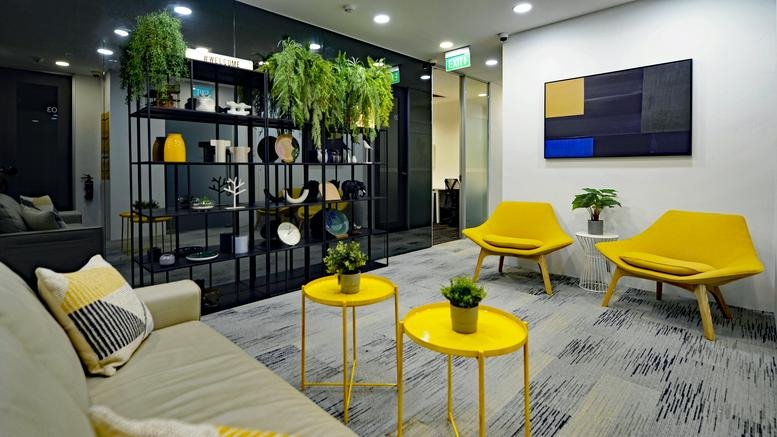 Modern lobby at Tong Eng Building with yellow chairs, potted plants, and abstract wall art.
