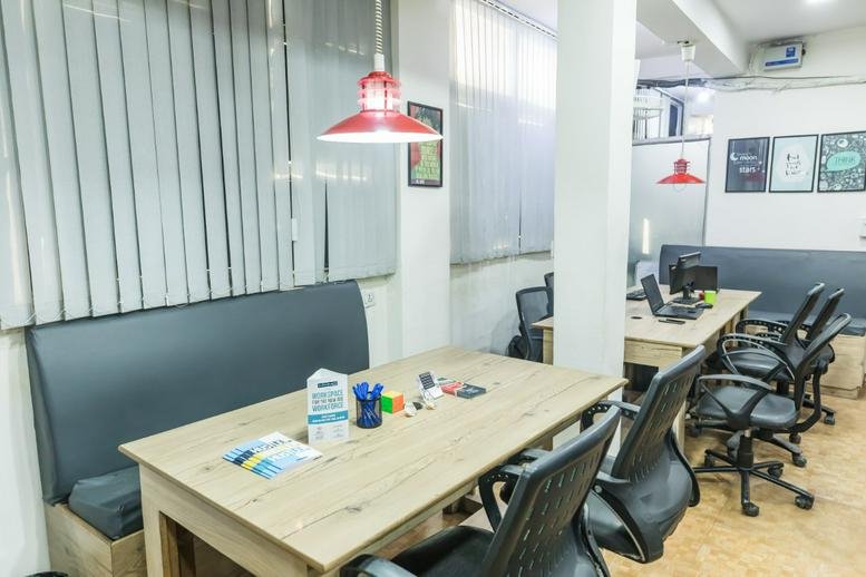 Spacious communal coworking area at 101, Pratap Nagar, Mayur Vihar Ph. 1, New Delhi with wooden tables and red lamps.