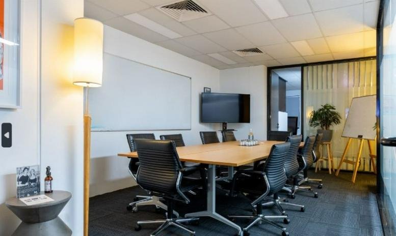 Spacious boardroom at 106-110 Parramatta Road, Level 1 with a large wooden table and black ergonomic chairs.