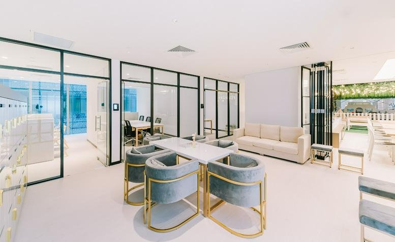 Spacious communal lounge with grey velvet armchairs and glass-walled offices at 109 North Bridge Road.
