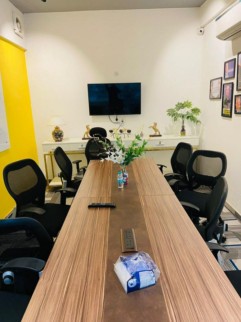 Meeting room at 1094, Huda Colony, Gurugram with wood-grain table and wall-mounted TV.