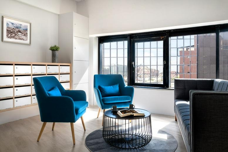 Lounge area at 10F, 235 Zhong Xiao East Rd featuring blue velvet armchairs and a modern coffee table.
