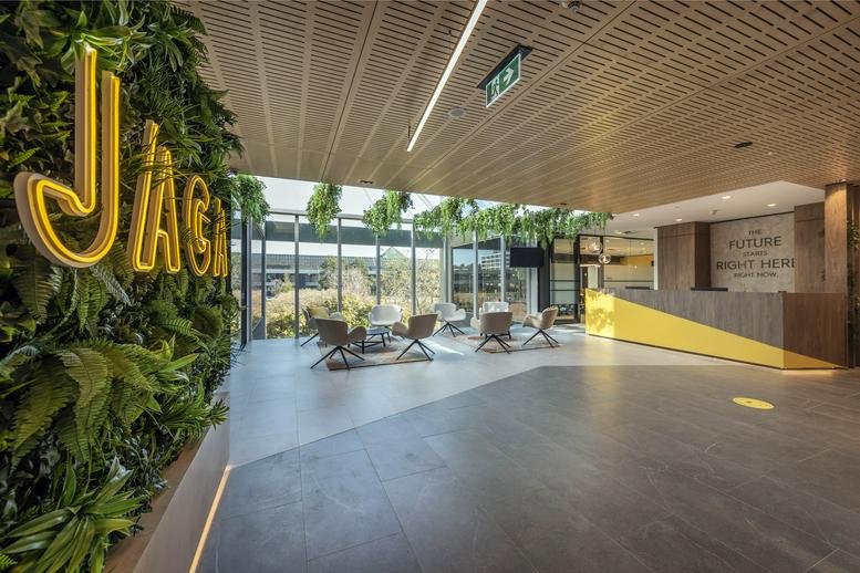 Reception area at Swanson Court, Belconnen, Canberra with a lush green feature wall and neon signage.