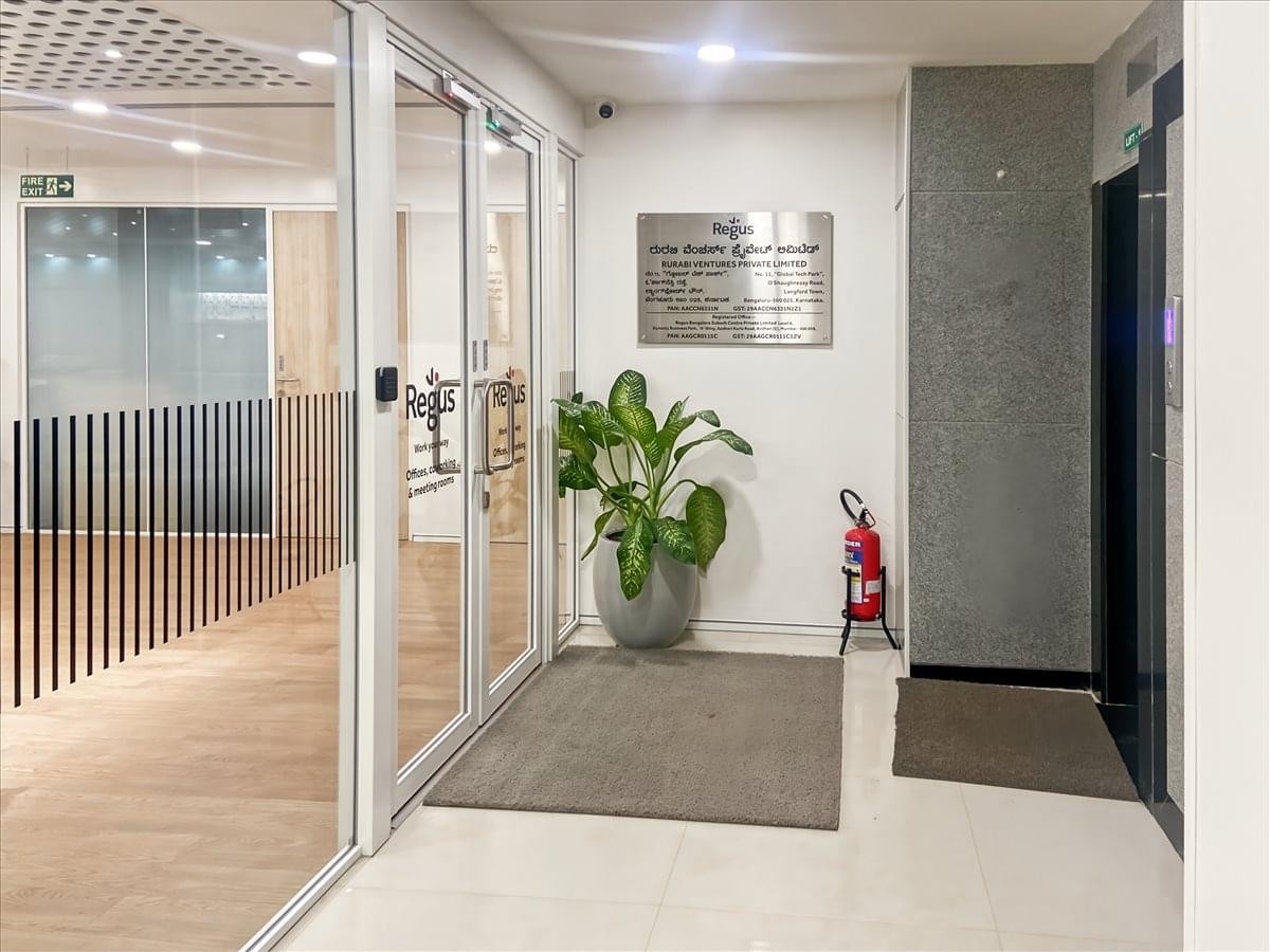 Entrance to Global Tech Park on O’ Shaughnessy Road featuring glass doors, a potted plant, and a directory plaque.