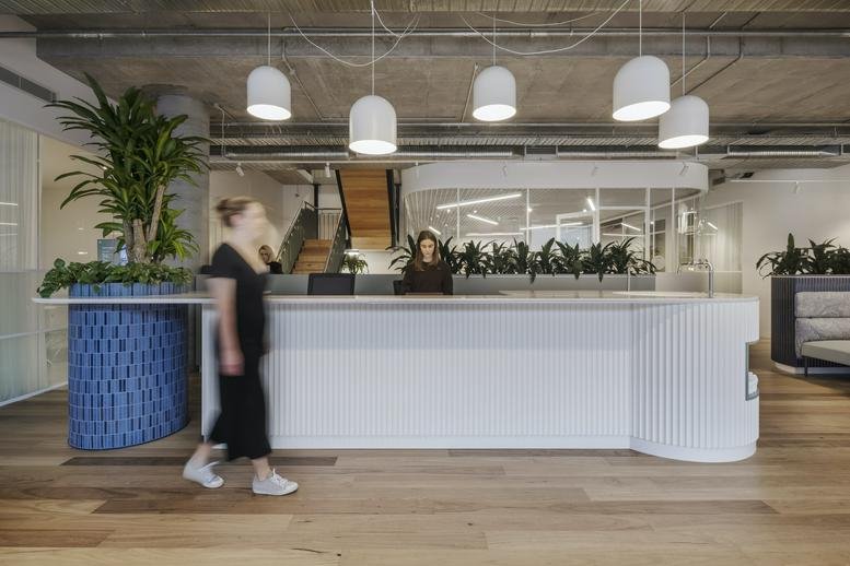Spacious reception area with a blue tiled desk and hanging pendant lights at 11 Wilson Street, Melbourne.