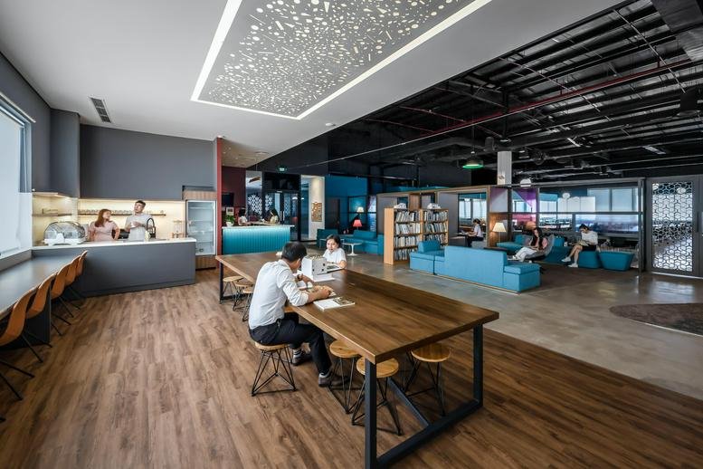 Vibrant common area at C Space Building with a cafe, library, and comfortable blue lounge seating.