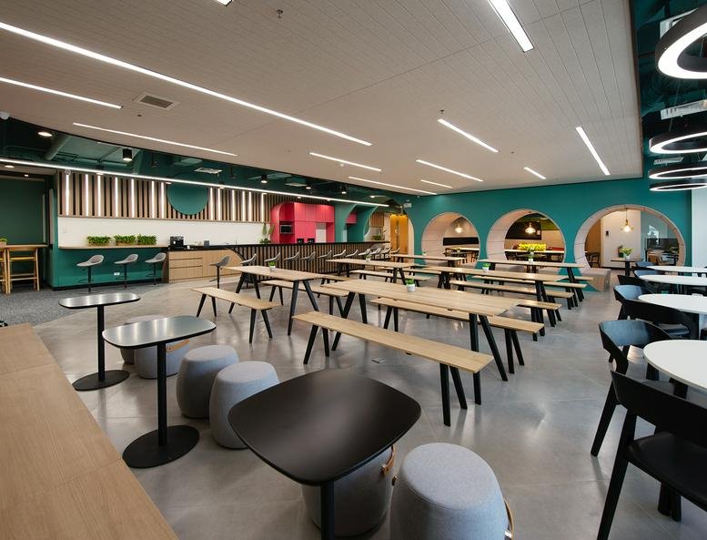 Spacious communal dining area at The Podium West Tower with modern wooden tables and teal accent walls.