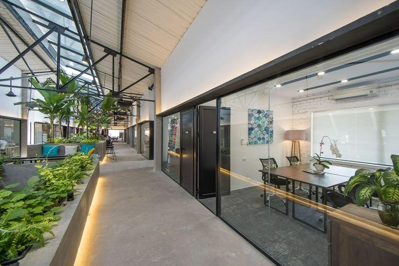 Wide view of a bright hallway featuring glass-walled offices and built-in planters.