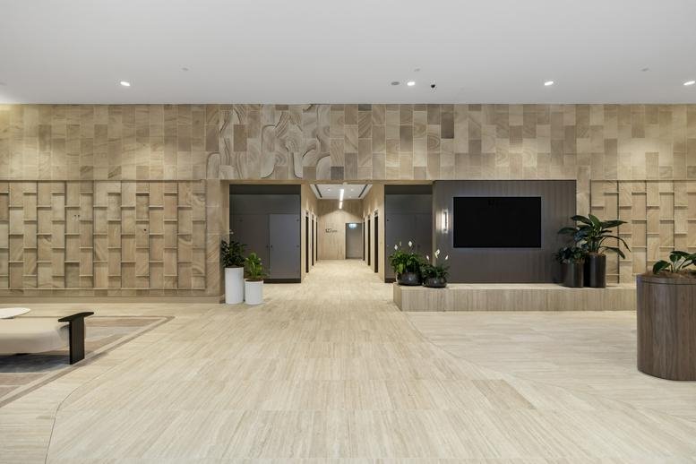 Polished elevator lobby with textured stone walls and a digital display screen.