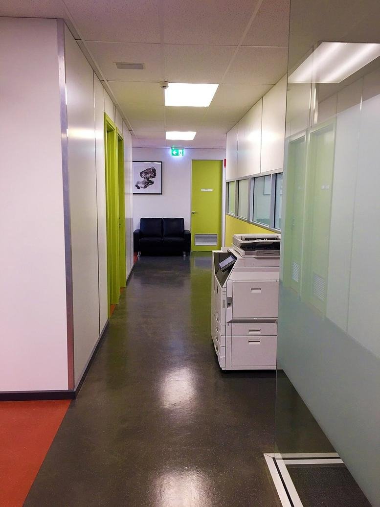 Corridor with a white printer and green door in an office setting