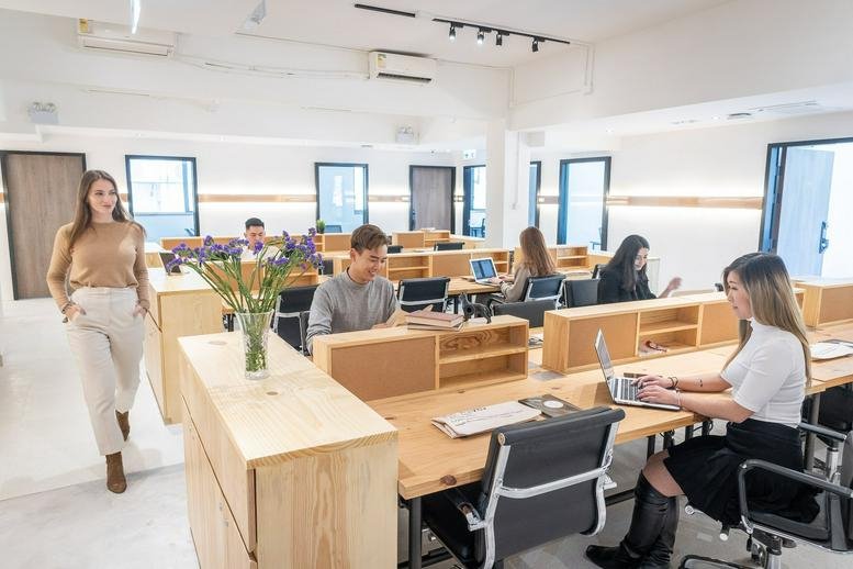 Spacious open-plan office at Liberal Factory Building featuring wooden desks and natural light.