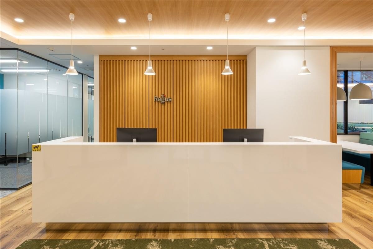 Minimalist white reception desk at 140 Kajimachi, AOI Tower C Building, Shizuoka under warm pendant lighting.