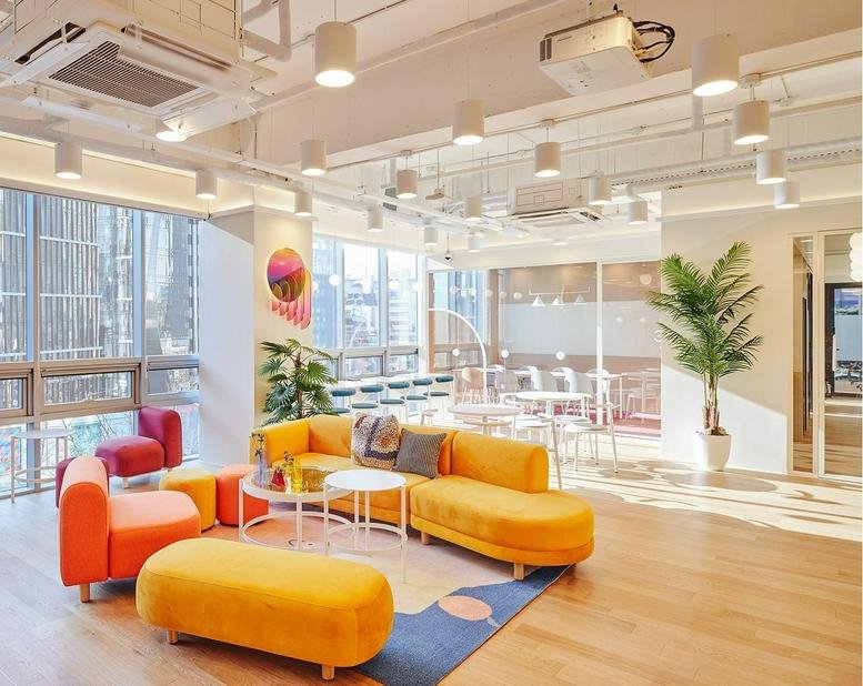 Vibrant communal lounge at 145 Dosan-daero, Sinsa 1, with a yellow sectional sofa and floor-to-ceiling windows.