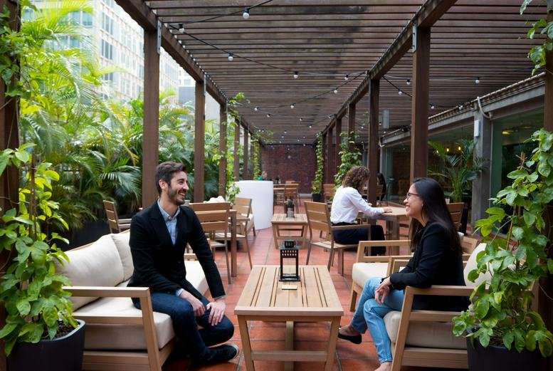 Spacious outdoor terrace lounge with wooden pergola and lush greenery at Manning House.