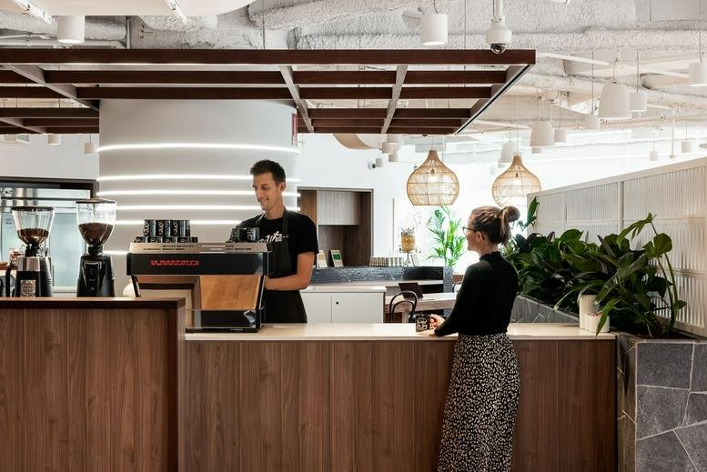 A modern cafe and kitchen area with a barista and a customer at 152 St Georges Terrace, Perth.