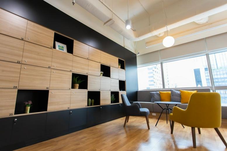 Spacious communal lounge with wooden lockers and modern yellow and blue seating at 159 Serm-mit Tower.