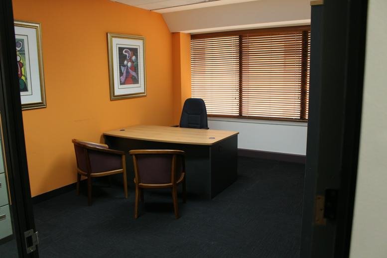 Private office featuring an orange accent wall and twin framed artworks.